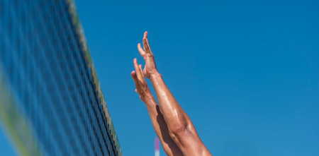 Athletic man jumping to make wall block at beach volleyball netの写真素材