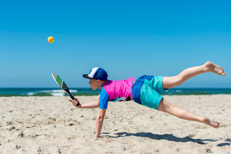 Young boy playing tennis on beach. Summer sport conceptの写真素材