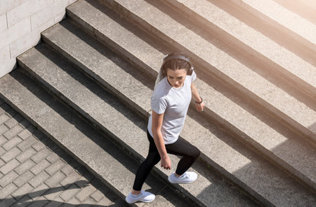 Woman listening music in city street. Sport activities on street and music