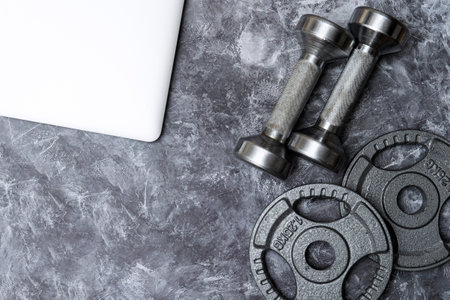 Grey dumbbells and laptop for fitness training on grey background. Workout online home. Horizontal sport poster, greeting cards, headers, website.の写真素材