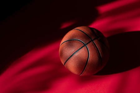 Basketball on red court floor with natural lighting. Workout online concept. Horizontal sport poster, greeting cards, headers, website and appの写真素材