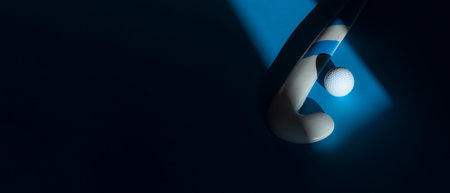 Field hockey stick and white ball with natural lighting on blue background. Sport team concept....