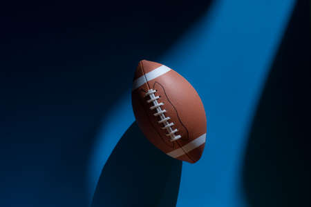 American football ball with natural lighting on blue background. Horizontal sport theme poster, greeting cards, headers, website and appの写真素材