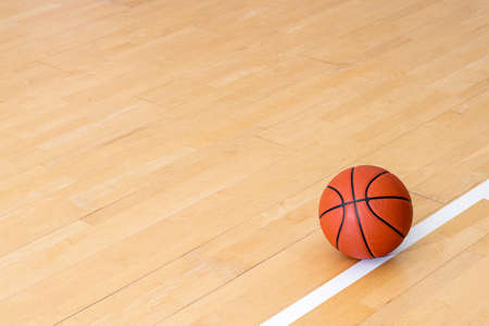 Basketball on hardwood court floor with natural lighting. Workout online concept. Horizontal sport theme poster, greeting cards, headers, website and appの写真素材
