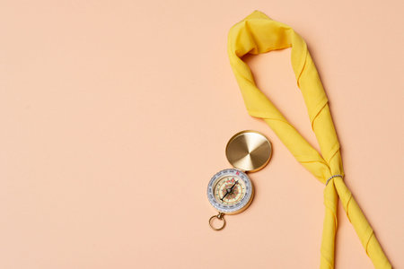 Yellow scarf of a scout and compass on beige background