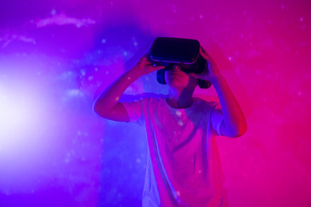 Young boy playing VR goggle on neon lighting. People, technology and cyberspace concept