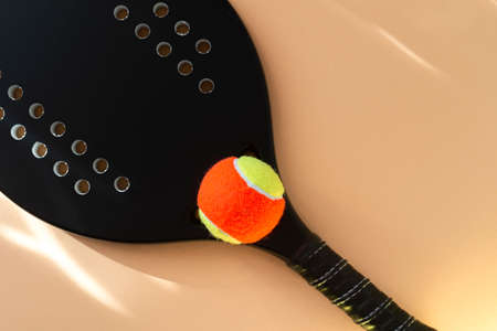 Black professional beach tennis racket and ball on beige background. Horizontal sport theme poster, greeting cards, headers, website and appの写真素材