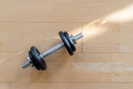 Dumbbell on wooden surface. Concept of rehabilitation and sport training equipment