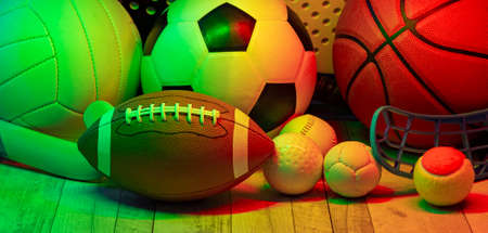 Sports equipment, rackets and balls on hardwood court floor with neon light background. Horizontal education and sport poster, greeting cards, headers, websiteの写真素材