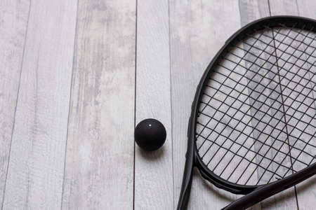 Black squash racket and ball on grey court. Horizontal sport theme poster, greeting cards, headers, website and appの写真素材