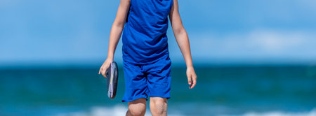 Young boy playing tennis on beach. Kids sport concept. Horizontal sport theme poster, greeting cards, headers, website and appの写真素材