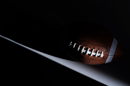 American football ball with natural lighting on dark background. Horizontal sport theme poster, greeting cards, headers, website and appの写真素材