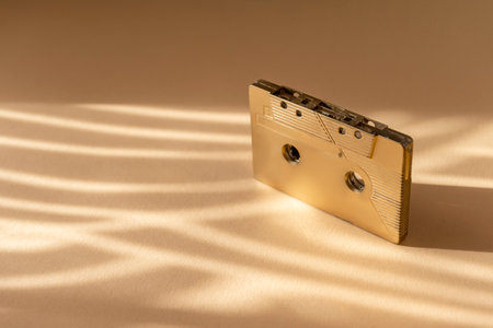 Gold fancy retro old audio cassette tape on beige color background. Retro mixtape, 1980s pop songs tapes and stereo music cassettesの写真素材