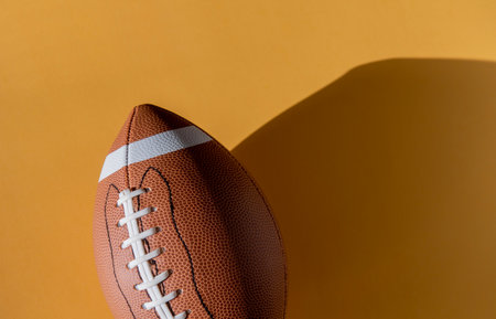 American football leather ball on yellow background. Top view. Game equipment horizontal sport theme poster, greeting cards, headers, website and appの写真素材