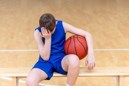 Sad disappointed boy with basketball ball in a physical education lessonの写真素材