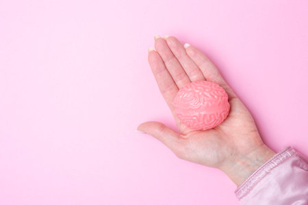 Hand holding pink brain isolated on pink backgroundの写真素材