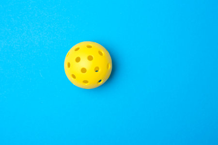 Yellow pickleball ball on blue background. Horizontal education and sport poster, greeting cards, headers, websiteの写真素材