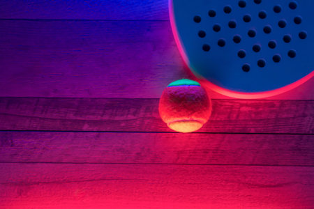 White professional paddle tennis racket and ball with neon lighting on wooden background. Horizontal sport theme poster, greeting cards, headers, website and appの写真素材