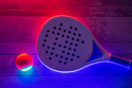 White professional paddle tennis racket and ball with neon lighting on wooden background. Horizontal sport theme poster, greeting cards, headers, website and appの写真素材