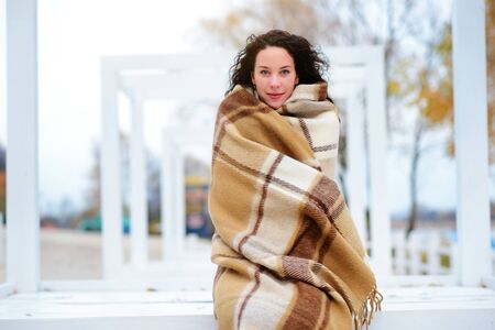 beautiful girl dressed in a blanket on the beach in gorgeous autumn dayの写真素材