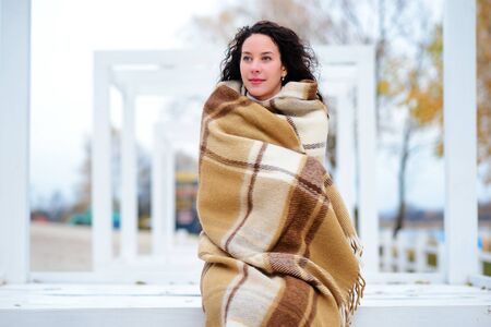 beautiful girl dressed in a blanket on the beach in gorgeous autumn dayの写真素材
