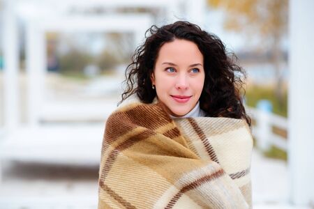 beautiful girl dressed in a blanket on the beach in gorgeous autumn dayの写真素材