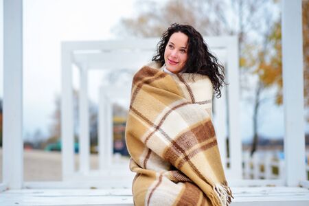 beautiful girl dressed in a blanket on the beach in gorgeous autumn dayの写真素材