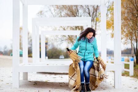 beautiful girl dressed in a blanket on the beach in gorgeous autumn dayの写真素材