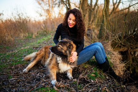Young woman playing with Caucasian shepherd in a delightful spring dayの写真素材