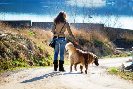 Young woman playing with Caucasian shepherd in a delightful spring dayの写真素材