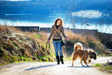 Young woman playing with Caucasian shepherd in a delightful spring dayの写真素材