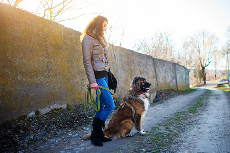 Young woman playing with Caucasian shepherd in a delightful spring dayの写真素材