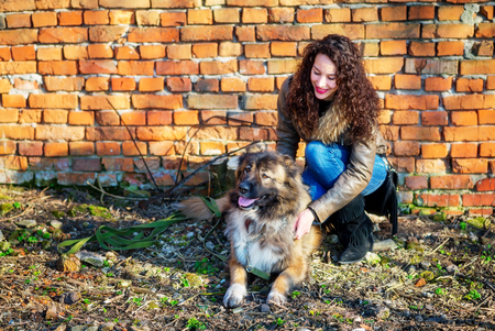 Young woman playing with Caucasian shepherd in a delightful spring dayの写真素材