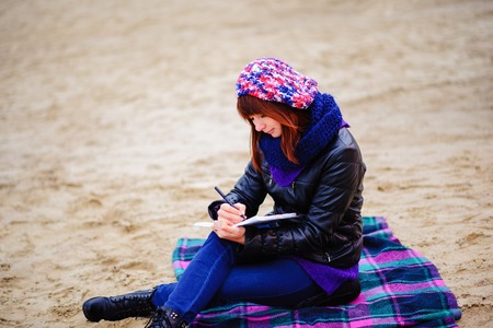 beautiful girl sitting on the beach and has records in a notebook, the appearance of the shoulderの写真素材