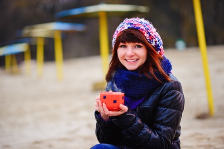 woman drinking coffee from her thermos, enjoying autumn evening by the seaの写真素材