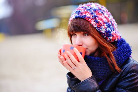 woman drinking coffee from her thermos, enjoying autumn evening by the seaの写真素材