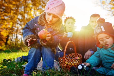 Girl sitting on the grass with an apple in his hand, early autumnの写真素材