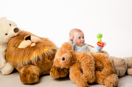 little girl sits among many plush toysの写真素材