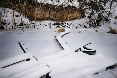 Frozen pond shore with boards laid out pathの写真素材