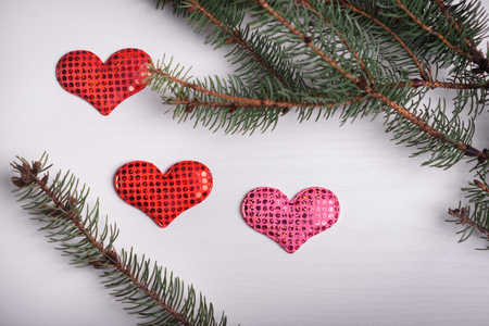Wooden white background with a branch of pine and three hearts. The concept for Valentine's Dayの写真素材