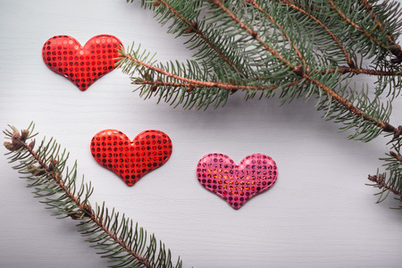 Wooden white background with a branch of pine and three hearts. The concept for Valentine's Dayの写真素材