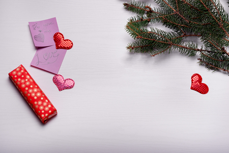 Wooden white background with a branch of pine and three hearts. The concept for Valentine's Dayの写真素材