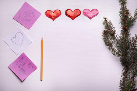Wooden white background with a branch of pine and three hearts. The concept for Valentine's Dayの写真素材
