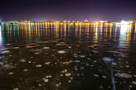 Frozen lake on the background of night cityの写真素材