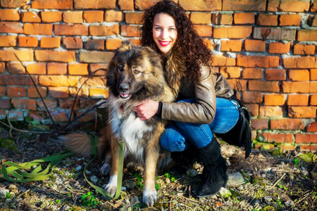 Young woman playing with Caucasian shepherd in a delightful spring dayの写真素材