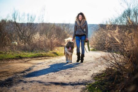 Young woman playing with Caucasian shepherd in a delightful spring dayの写真素材