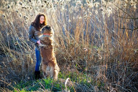 Young woman playing with Caucasian shepherd in a delightful spring dayの写真素材