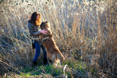Young woman playing with Caucasian shepherd in a delightful spring dayの写真素材