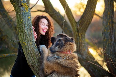 Young woman playing with Caucasian shepherd in a delightful spring dayの写真素材