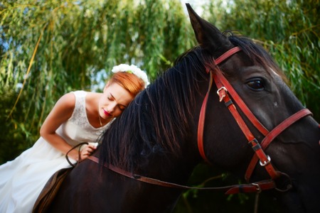 Portrait of a bride on horseback on the background of a summer sunset.の写真素材